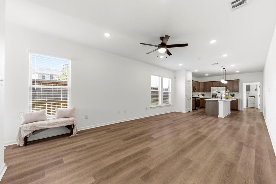 Spacious open-concept living area with luxury vinyl plank flooring, abundant natural light, and seamless flow into the kitchen and dining spaces.