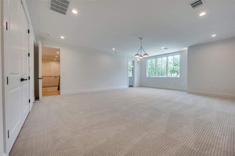 Empty room featuring light carpet, a chandelier, and recessed lighting