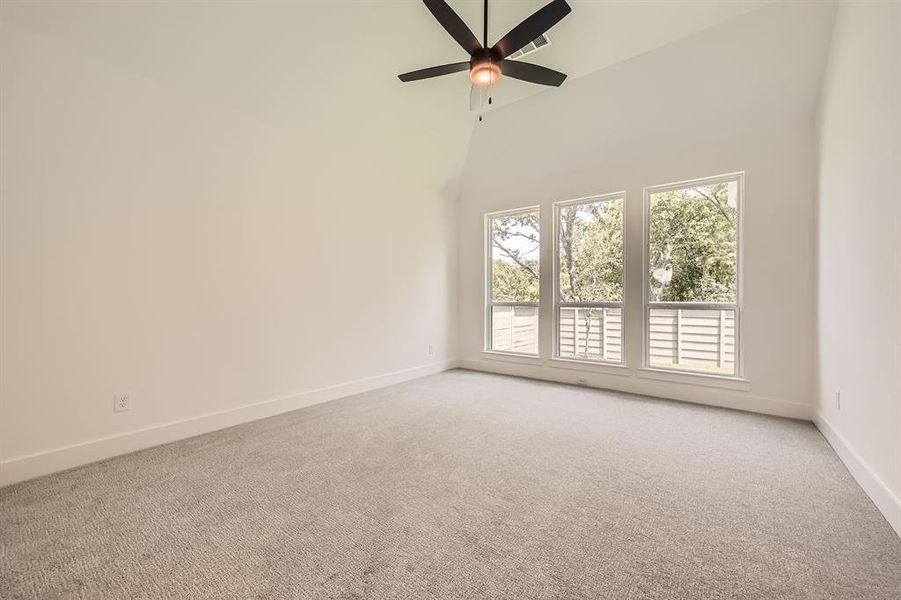 Spare room with light colored carpet, baseboards, ceiling fan, and high vaulted ceiling
