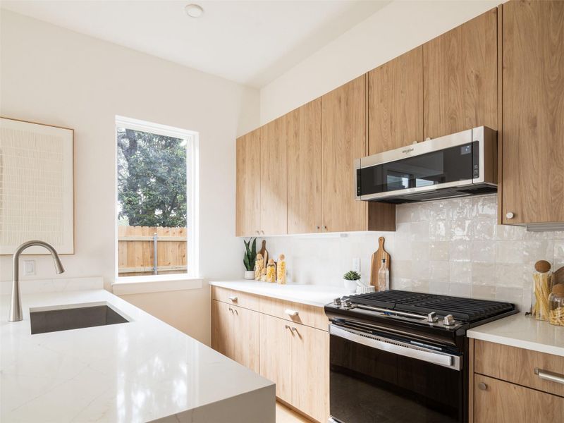 Modern kitchen featuring light wood-finish cabinetry and white countertops