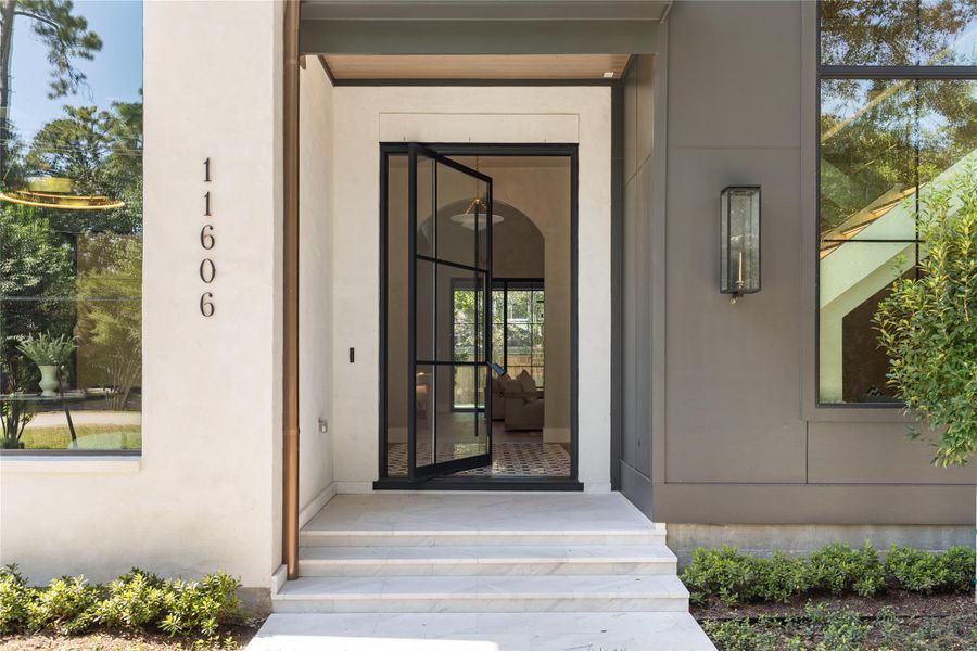 A custom glass and iron pivot door creates a striking and inviting entrance. A custom glass and iron pivot door creates a striking and inviting entrance.