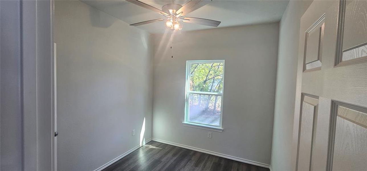 Spare room featuring dark wood finished floors and ceiling fan