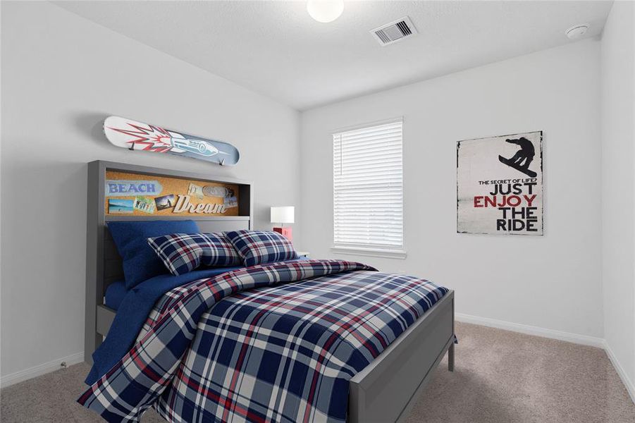 Secondary bedroom features plush carpet, custom paint, lighting, ample closet space, and a large window with privacy blinds.