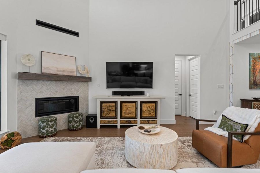 A striking fireplace with a herringbone tile surround anchors this inviting living space, crowned by soaring ceilings. A striking fireplace with a herringbone tile surround anchors this inviting living space, crowned by soaring ceilings.
