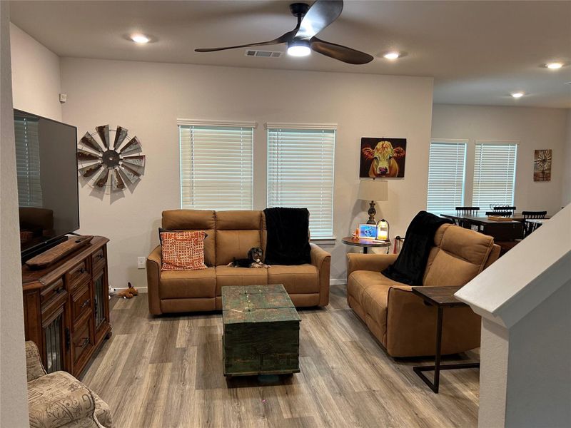 Expansive living area with wood-finish flooring, recessed lighting, and a ceiling fan