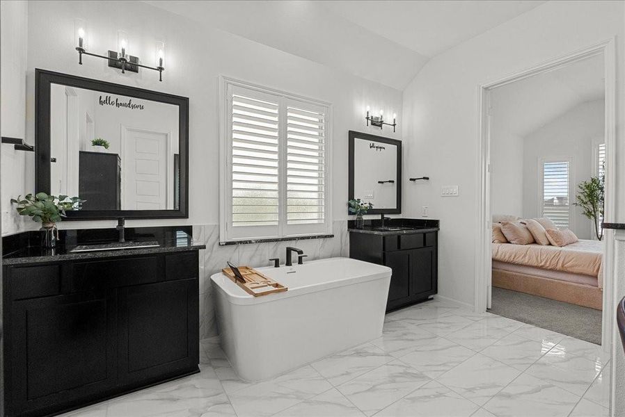 The luxurious primary en-suite bath features dual vanities, a walk-in shower, soaking tub, and separate his-and-her walk-in closets.