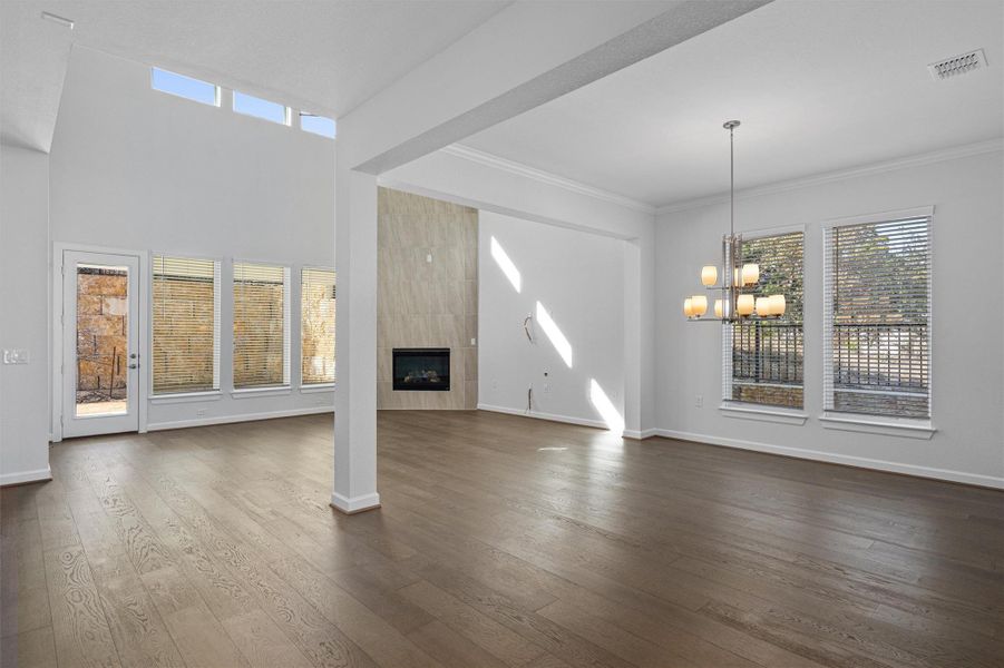 Unfurnished living room featuring a fireplace, dark wood finished floors, a chandelier, and ornamental molding Unfurnished living room featuring a fireplace, dark wood finished floors, a chandelier, and ornamental molding