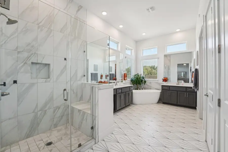 The spa-inspired primary bathroom exudes tranquility with separate vanities, a freestanding soaking tub, and an oversized walk-in shower.