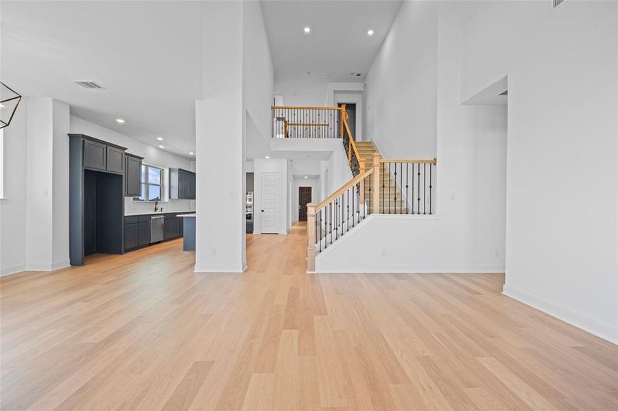 Unfurnished living room with sink, light hardwood / wood-style floors, and a high ceiling