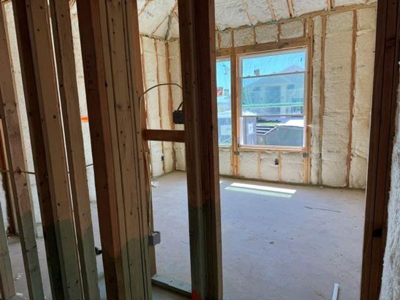 An interior space under construction features wooden framing and insulation, awaiting final finishes.