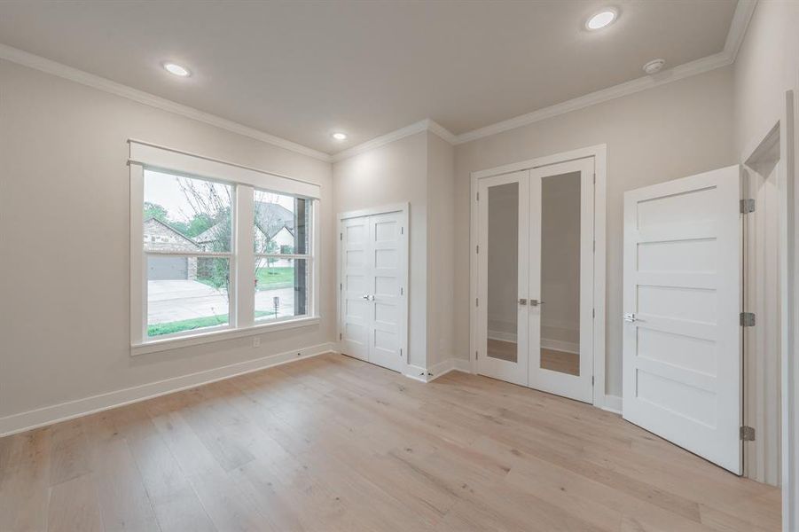 Unfurnished bedroom featuring french doors, ornamental molding, light wood-style floors, recessed lighting, and a closet