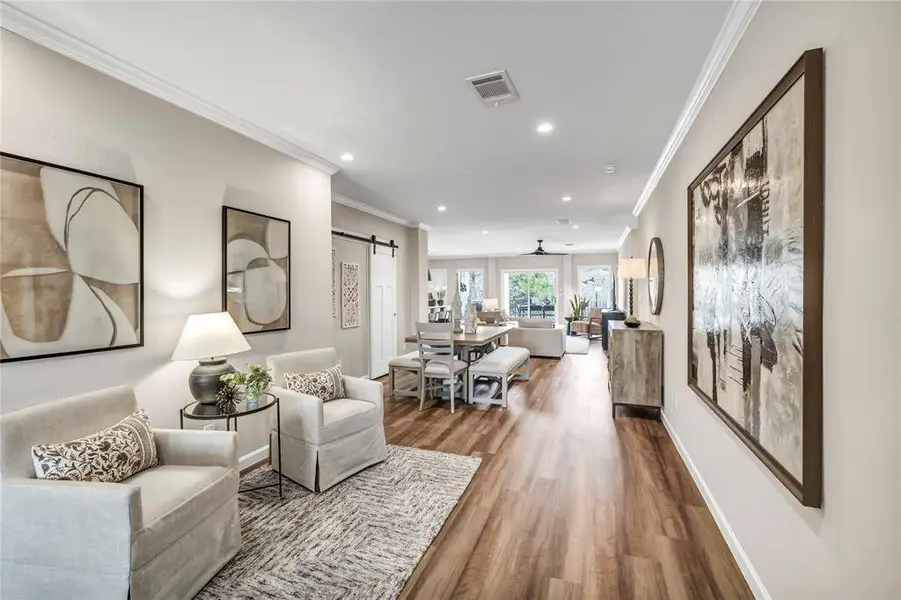 Living room featuring a barn door, ornamental molding, wood finished floors, and recessed lighting