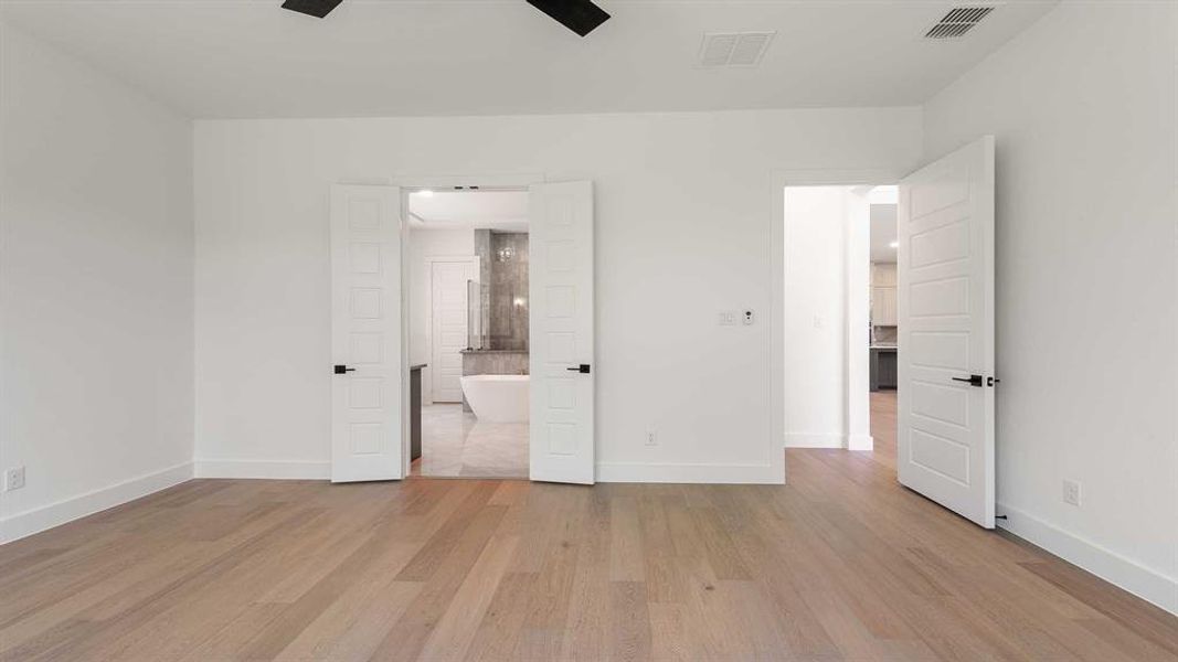 Unfurnished bedroom featuring light wood-type flooring, ensuite bath, and a ceiling fan
