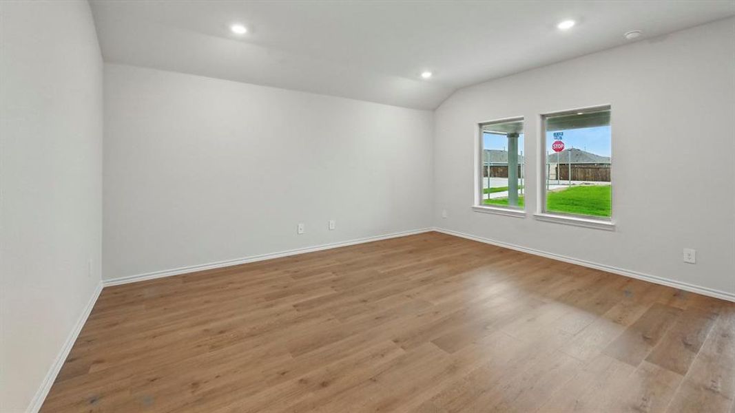Spare room featuring vaulted ceiling, wood finished floors, and recessed lighting
