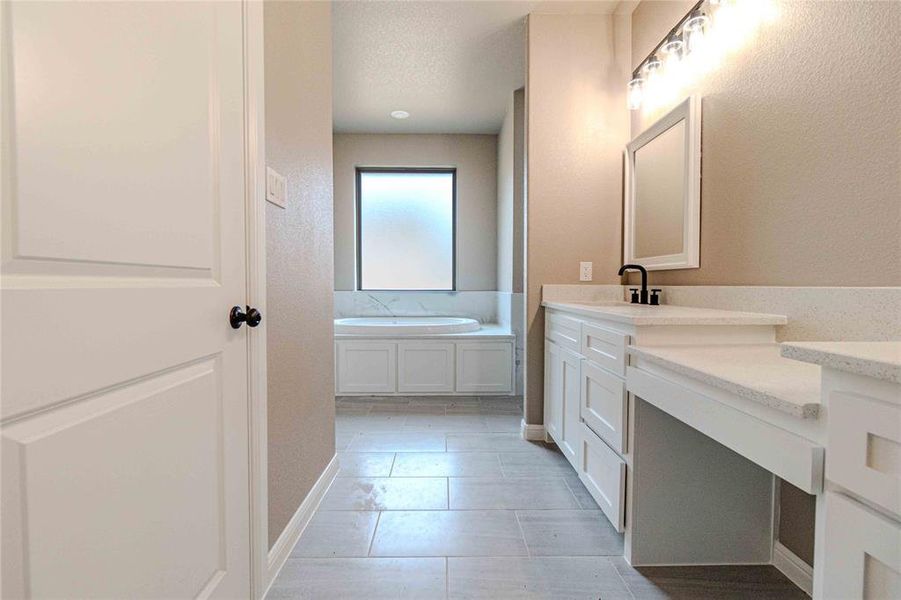 Bathroom featuring a tub to relax in, vanity, and tile patterned flooring