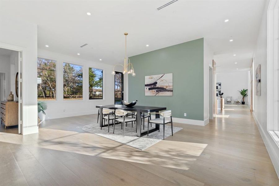 Dining room with light wood-type flooring and a notable chandelier