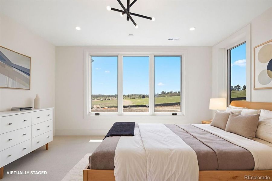 Lower level bedroom with large windows and a modern pendant light. *This photo has been virtually staged