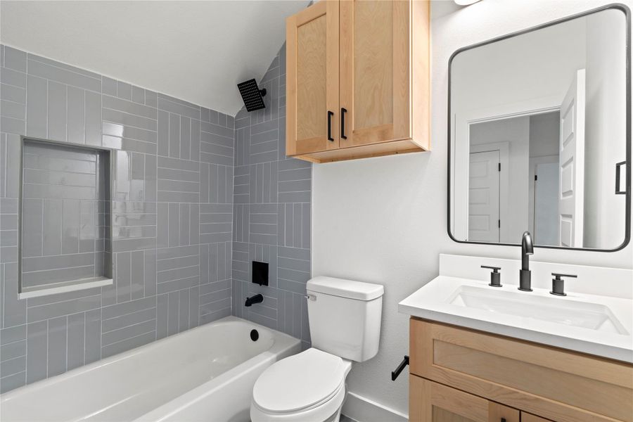 Contemporary tilework wraps the tub-shower combo in designer style, with vertical and horizontal lines creating visual rhythm.