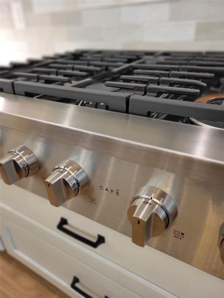 This photo shows a modern stainless steel CAFE gas stove with sleek control knobs, ideal for a contemporary kitchen. This photo shows a modern stainless steel CAFE gas stove with sleek control knobs, ideal for a contemporary kitchen.