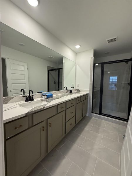 Full bathroom featuring a stall shower, double vanity, and light tile patterned floors