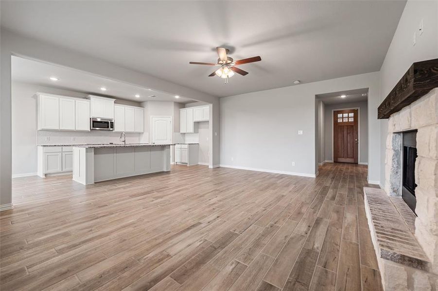 Unfurnished living room featuring recessed lighting, a fireplace with raised hearth, ceiling fan, and light wood-style floors Unfurnished living room featuring recessed lighting, a fireplace with raised hearth, ceiling fan, and light wood-style floors