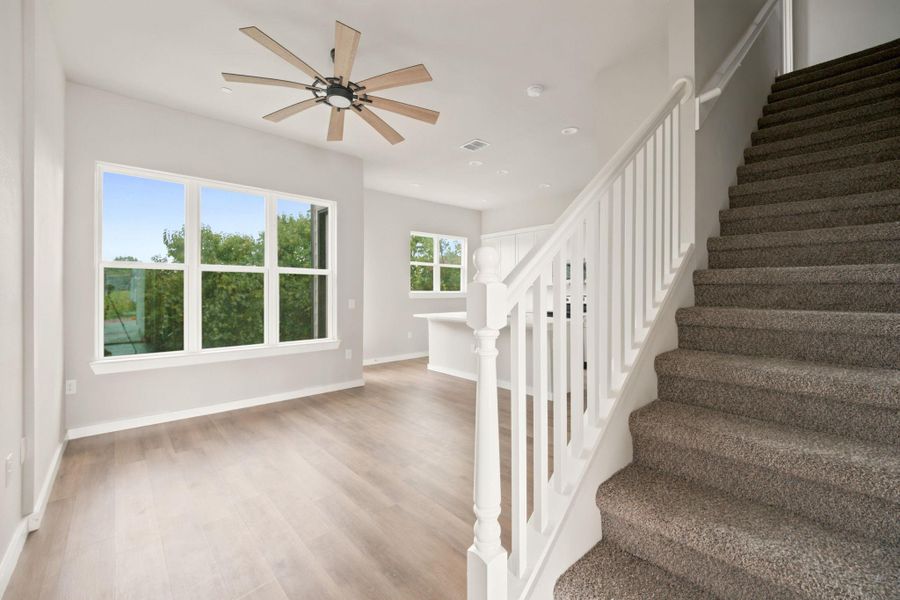 An open floor plan connects the living area with a carpeted staircase leading upstairs.