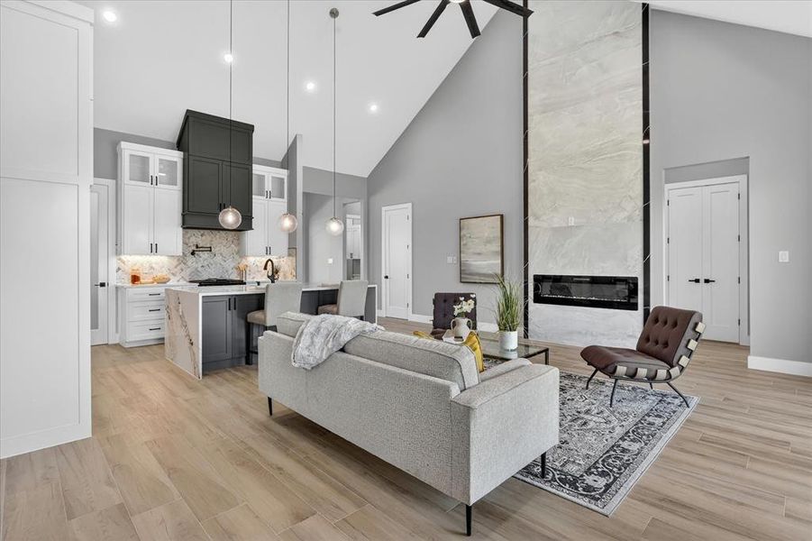 Open-concept living area featuring vaulted ceilings, wood-finish flooring, and a floor-to-ceiling fireplace with an electric insert