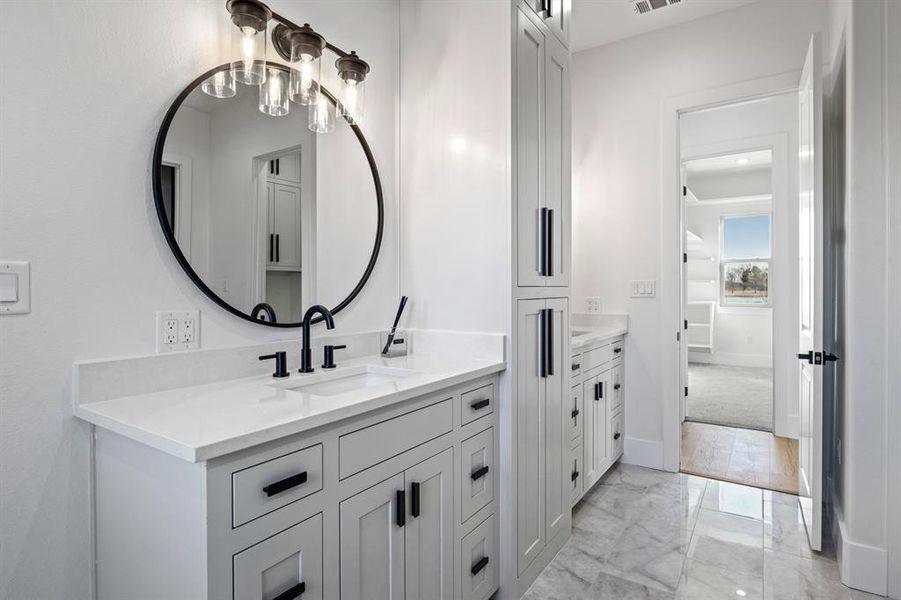 Bathroom featuring visible vents, baseboards, a sink, two vanities, and marble finish floor Bathroom featuring visible vents, baseboards, a sink, two vanities, and marble finish floor
