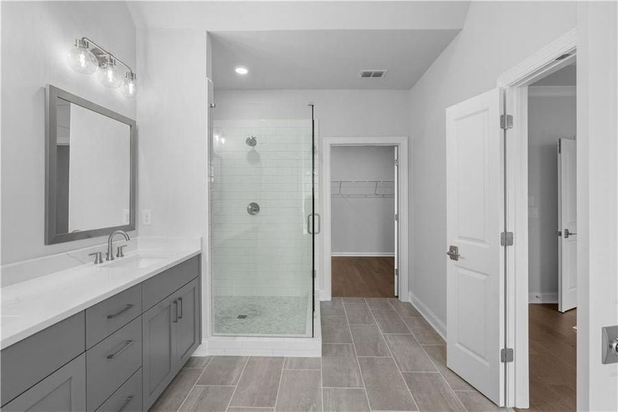 Full bathroom featuring a stall shower, vanity, light wood-style flooring, a spacious closet, and recessed lighting Full bathroom featuring a stall shower, vanity, light wood-style flooring, a spacious closet, and recessed lighting
