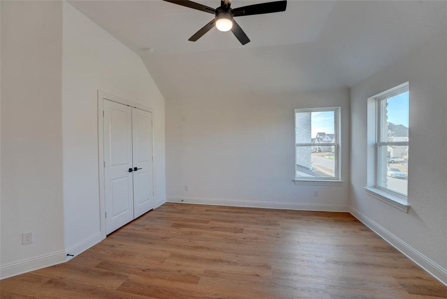 Bedroom featuring vinyl flooring, baseboards, a ceiling fan, and lofted ceiling