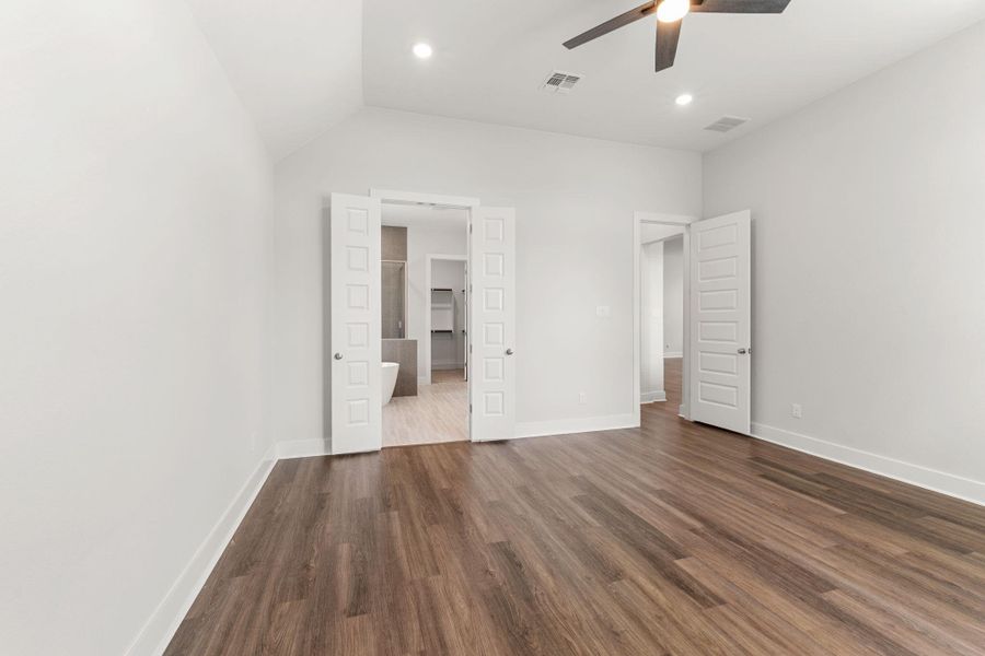 Unfurnished bedroom with a spacious closet, dark wood-type flooring, baseboards, vaulted ceiling, and a ceiling fan Unfurnished bedroom with a spacious closet, dark wood-type flooring, baseboards, vaulted ceiling, and a ceiling fan