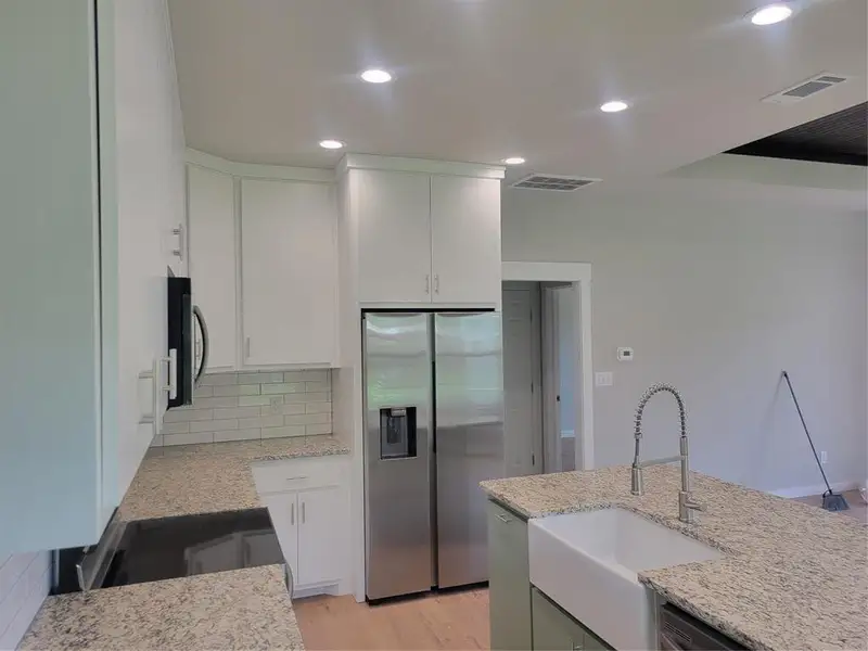 Modern kitchen featuring white shaker cabinetry, stainless steel appliances, granite countertops, subway tile backsplash, and recessed lighting