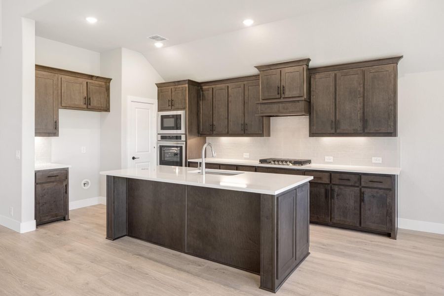 Kitchen with dark wood cabinets, large center island with white countertops, and stainless steel appliances Kitchen with dark wood cabinets, large center island with white countertops, and stainless steel appliances