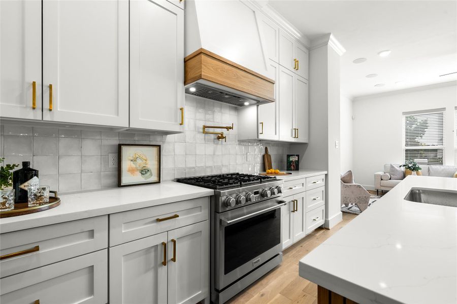 This gourmet kitchen is equipped with a premium Thor 6-burner gas range, complemented by a sleek pot filler and custom wood-accented vent hood - blending luxury, functionality, and timeless design.