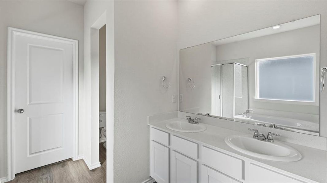 Full bath with double vanity, a garden tub, dark wood-style floors, and a shower stall