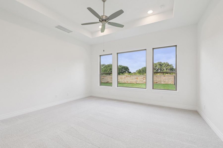 Empty room featuring a tray ceiling, light carpet, a ceiling fan, and recessed lighting