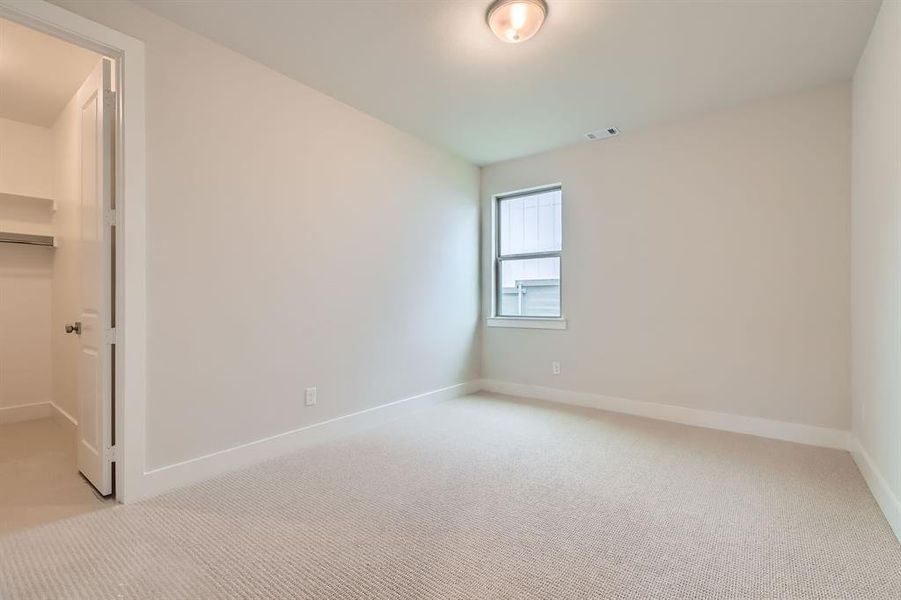 Unfurnished bedroom featuring light carpet, a walk in closet, and a closet Unfurnished bedroom featuring light carpet, a walk in closet, and a closet
