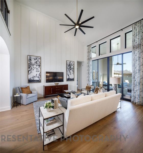 Living room with high vaulted ceiling, a ceiling fan, wood finished floors, and arched walkways
