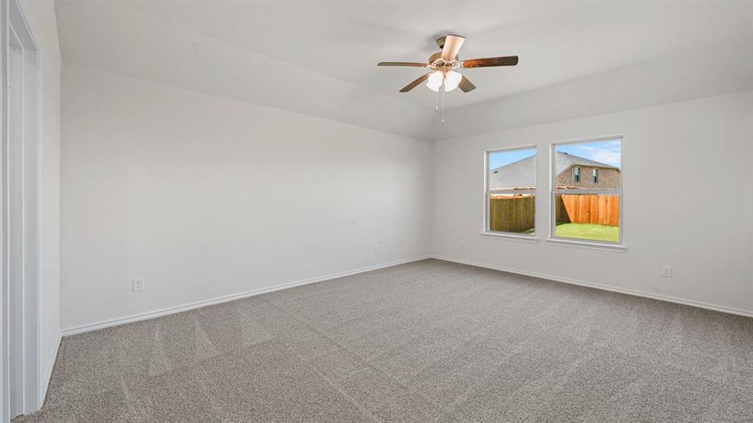 Spacious interior room featuring light gray carpet flooring, white walls, two windows, and a ceiling fan with light fixture