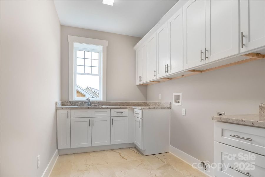 Huge laundry room with large tile floors, granite countertops and lots of cabinets for storage. Electric dryer connection and sink.