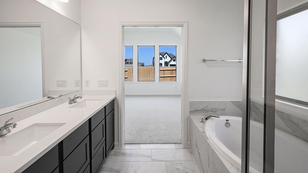 Bathroom with double vanity, a bath, and light marble finish flooring Bathroom with double vanity, a bath, and light marble finish flooring