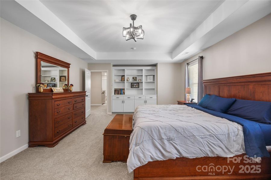 Huge primary bedroom features tray ceilings and custom built-ins. Huge primary bedroom features tray ceilings and custom built-ins.