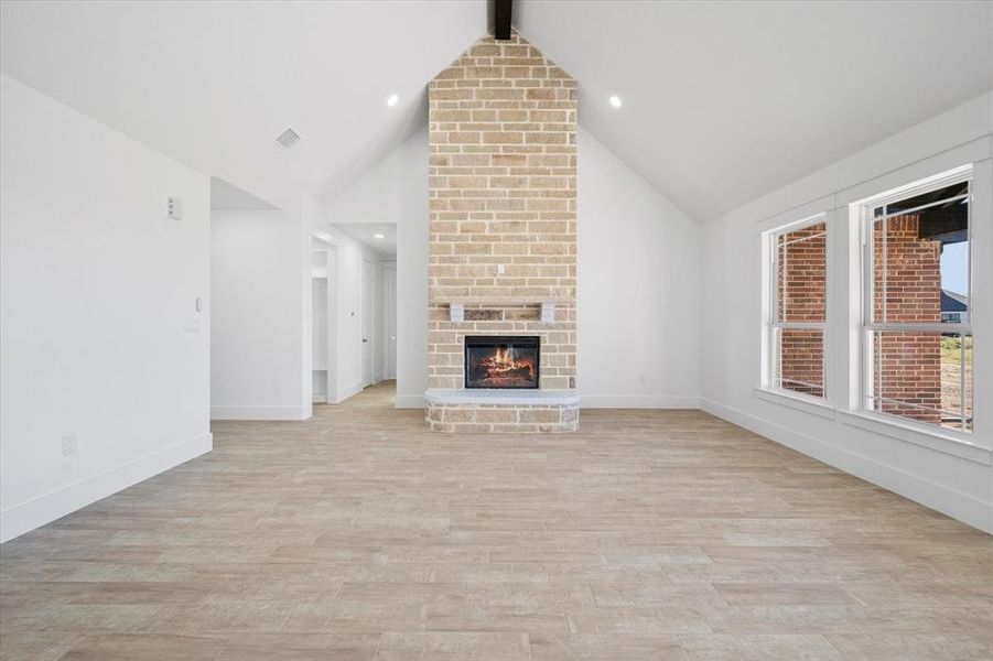 Unfurnished living room with lofted ceiling with beams, light hardwood / wood-style floors, and a fireplace