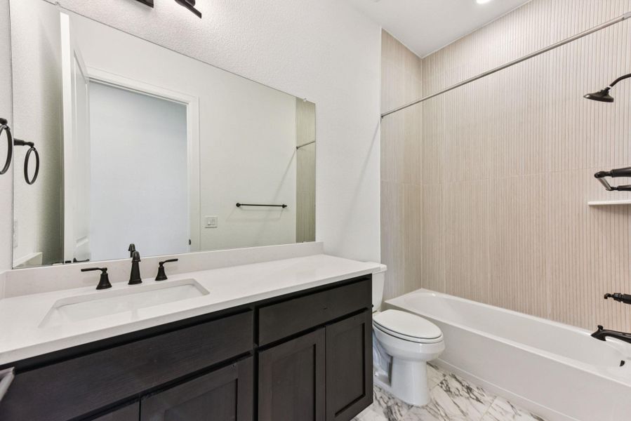 Full bath featuring bathtub / shower combination, vanity, and light marble finish floors