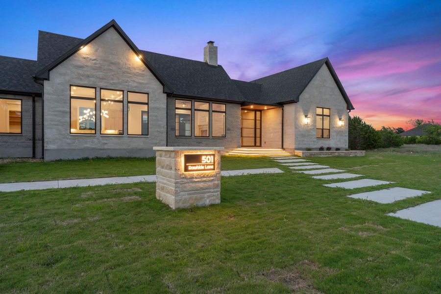 Contemporary stucco exterior featuring a dark asphalt shingle roof and black-framed windows