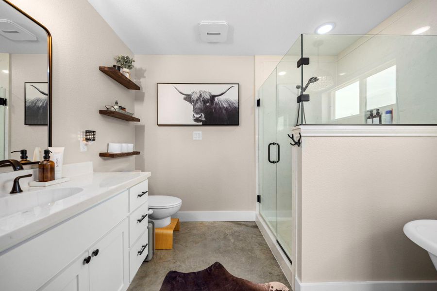 Full bathroom with vanity, a shower stall, unfinished concrete floors, and a freestanding bath