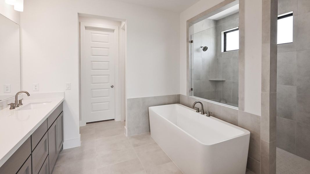 Full bathroom featuring a freestanding bath, vanity, a tile shower, tile walls, and tile patterned floors Full bathroom featuring a freestanding bath, vanity, a tile shower, tile walls, and tile patterned floors