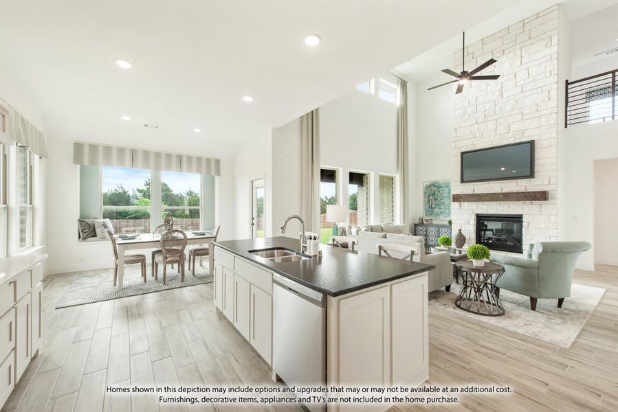 Open-concept kitchen with dark island countertop flowing into living room with stone fireplace and dining area