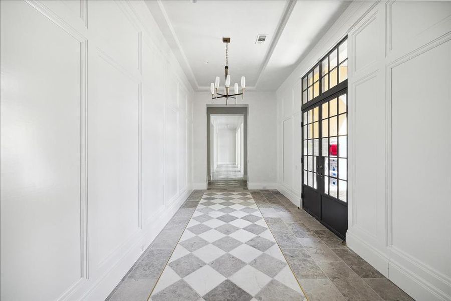 The luxurious foyer features iron double doors with glass inlays, lacquered walls, elegant marble flooring, and high ceilings.