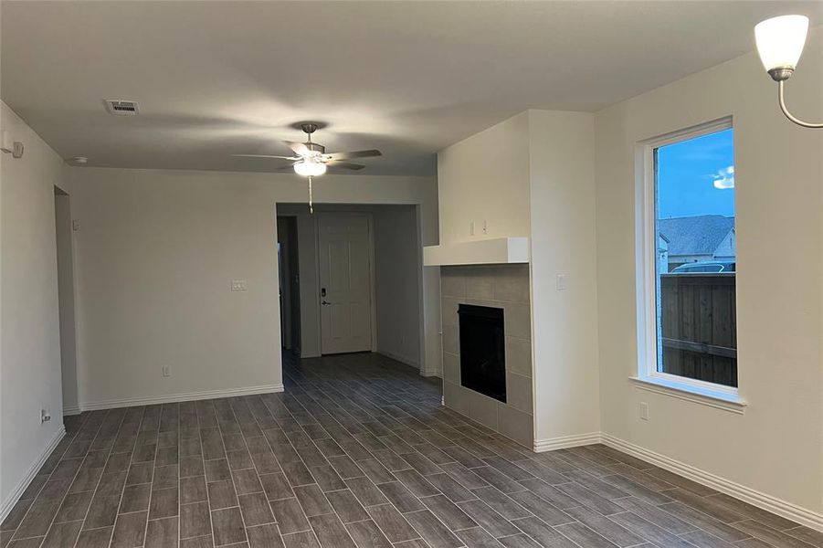 Unfurnished living room with a fireplace, ceiling fan, and wood finish floors Unfurnished living room with a fireplace, ceiling fan, and wood finish floors